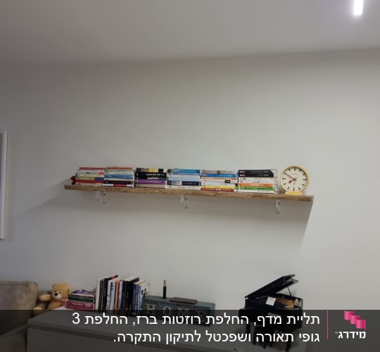 מדף עץ עם ספרים ושעון על הקיר